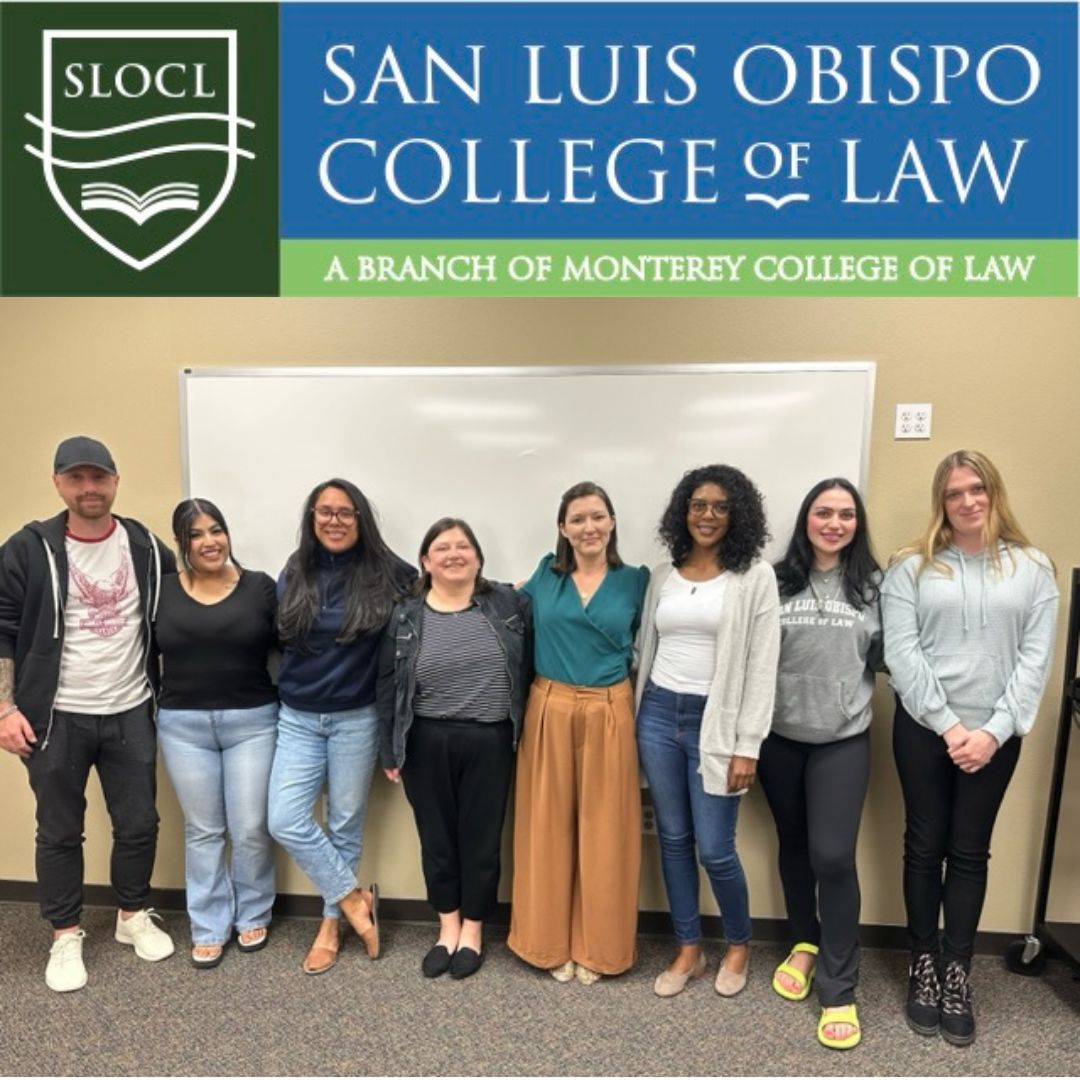 Diverse students standing in front of a white board in a classroom.