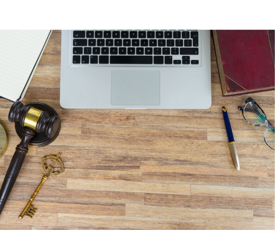 Picture of a laptop computer on a desk with a law gavel and a book